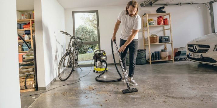Un homme nettoie le sol du garage avec un aspirateur Kärcher